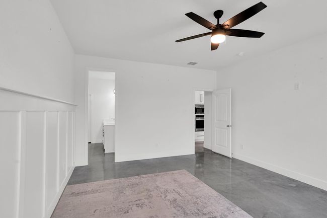 Spare room featuring finished concrete floors, baseboards, and a ceiling fan | Image 22