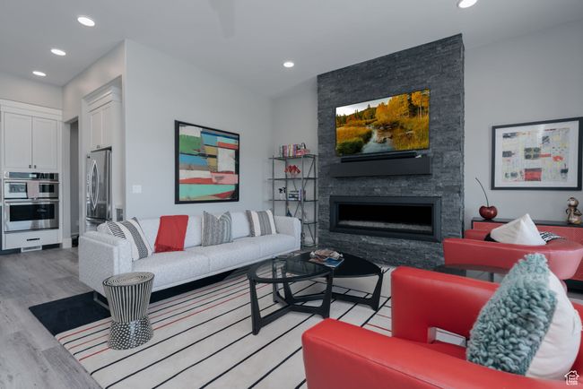 Living area featuring light wood-type flooring, recessed lighting, and a stone fireplace | Image 13
