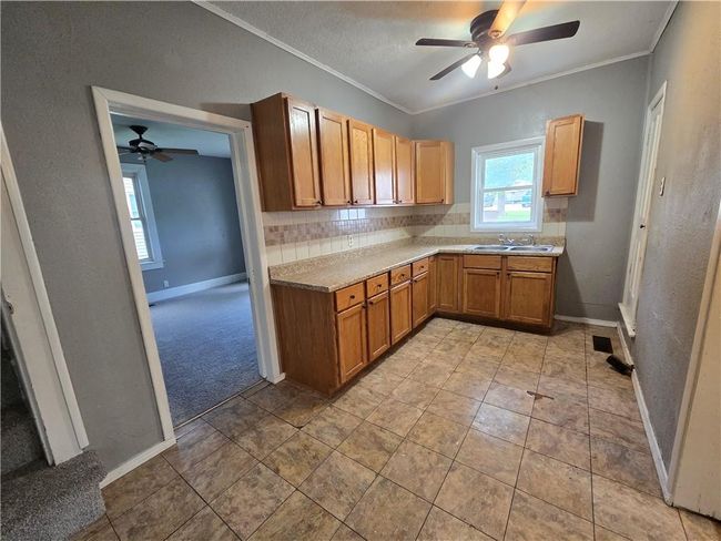 Kitchen with a ceiling fan, baseboards, crown molding, tasteful backsplash, and light countertops | Image 7