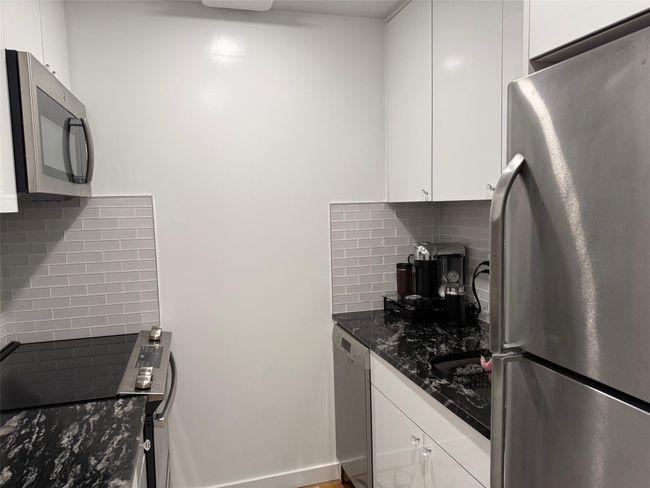 Kitchen featuring appliances with stainless steel finishes, backsplash, white cabinets, and dark stone countertops | Image 5