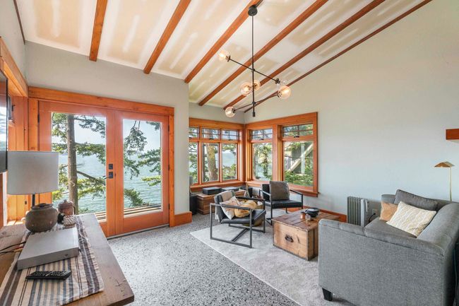 Living area featuring speckle patterned floor, a chandelier, lofted ceiling, french doors, and a water view | Image 15