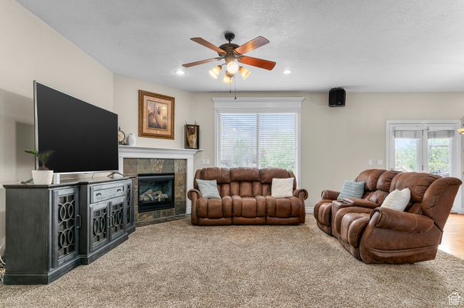 Carpeted living room featuring a tile fireplace, a healthy amount of sunlight, a ceiling fan, and recessed lighting | Image 6
