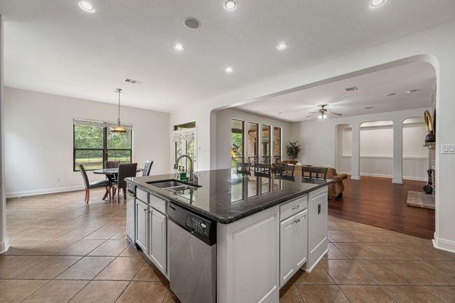Kitchen featuring arched walkways, stainless steel dishwasher, a sink, visible vents, and a center island with sink | Image 12