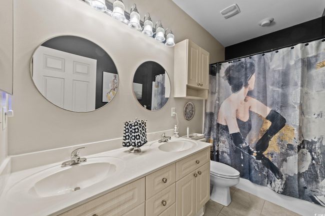 Bathroom with tile patterned floors, double vanity, toilet, and curtained shower | Image 11