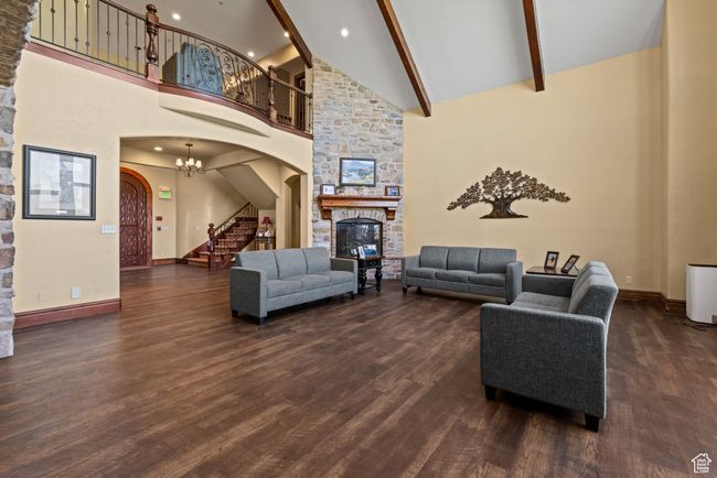 Living area featuring arched walkways, dark wood-style flooring, a fireplace, stairway, and high vaulted ceiling | Image 20