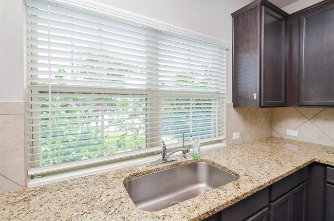 A roomy farmhouse style stainless steel sink sits below huge double windows. | Image 8