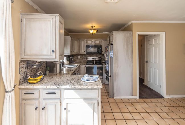 Kitchen featuring tasteful backsplash, a sink, light tile patterned floors, baseboards, and appliances with stainless steel finishes | Image 10