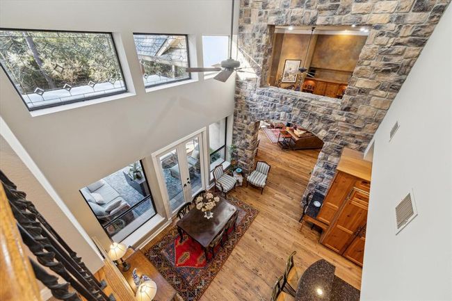 Spectacular view of the treetops from the balcony overseeing breakfast area with its soaring 20' ceiling, closely approaching the beautiful, custom-designed, insulated leaded-glass transoms. The view extends through the stone transom into the living room, emphasizing the home's grandeur. | Image 29