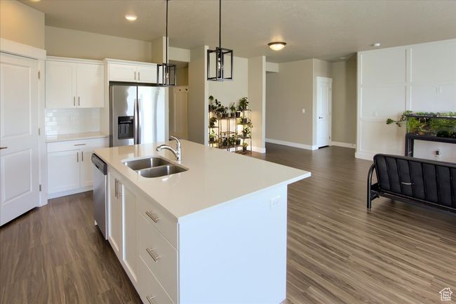 Kitchen featuring a sink, dark wood-style flooring, light countertops, appliances with stainless steel finishes, and an island with sink | Image 11
