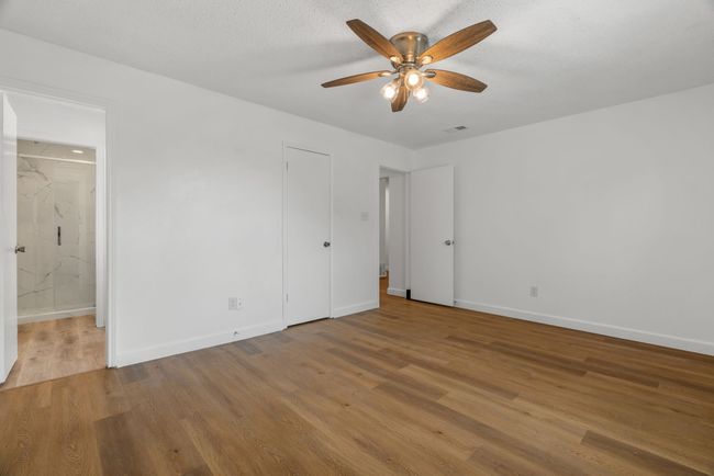Unfurnished bedroom featuring wood finished floors, connected bathroom, and a ceiling fan | Image 22