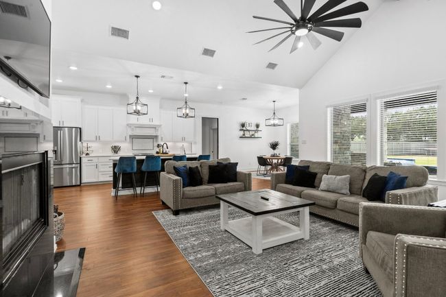 Living room with ceiling fan with notable chandelier, high vaulted ceiling, and visible vents | Image 14