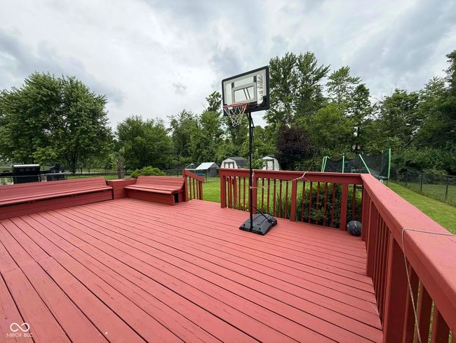 deck with a storage shed, a trampoline, a fenced backyard, and view of wooded area | Image 8