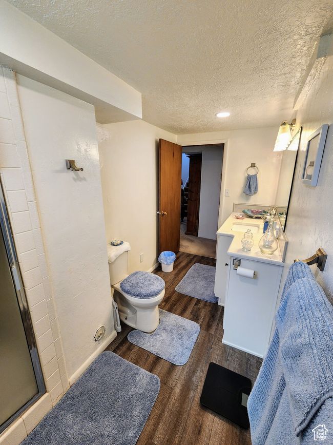 Bathroom with vanity, toilet, a textured ceiling, a shower stall, and wood finished floors | Image 39