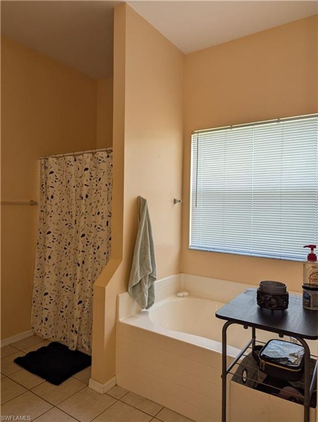 Full bathroom featuring tile patterned floors, a garden tub, and a shower with shower curtain | Image 11