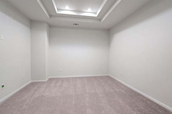 Empty room featuring baseboards, a tray ceiling, visible vents, and light carpet | Image 25