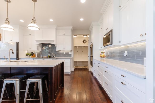 Kitchen with stainless steel appliances, decorative backsplash, white cabinets, a breakfast bar, and recessed lighting | Image 9
