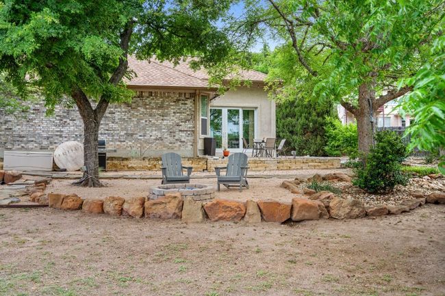 Rear view of house featuring a shingled roof, a patio area, french doors, an outdoor fire pit, and brick siding | Image 37