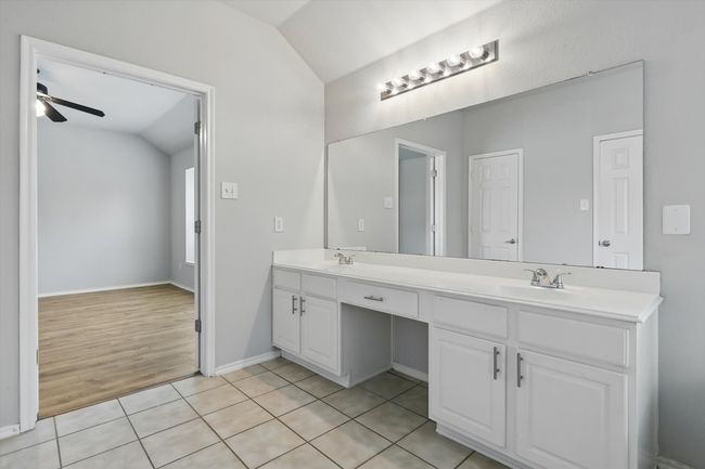Bathroom featuring vaulted ceiling, double vanity, a ceiling fan, and tile patterned flooring | Image 21