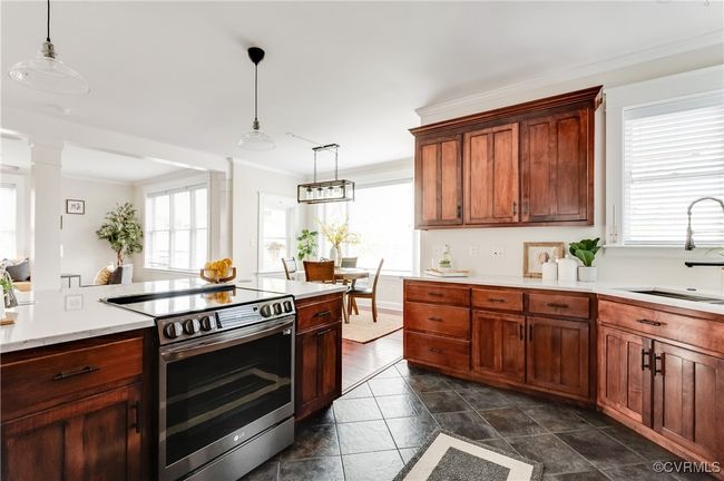Kitchen featuring light countertops, crown molding, stainless steel range with electric cooktop, a sink, and hanging light fixtures | Image 13
