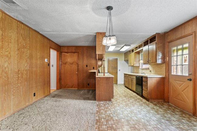 Kitchen featuring dishwasher, wood walls, light countertops, brown cabinetry, and a textured ceiling | Image 4