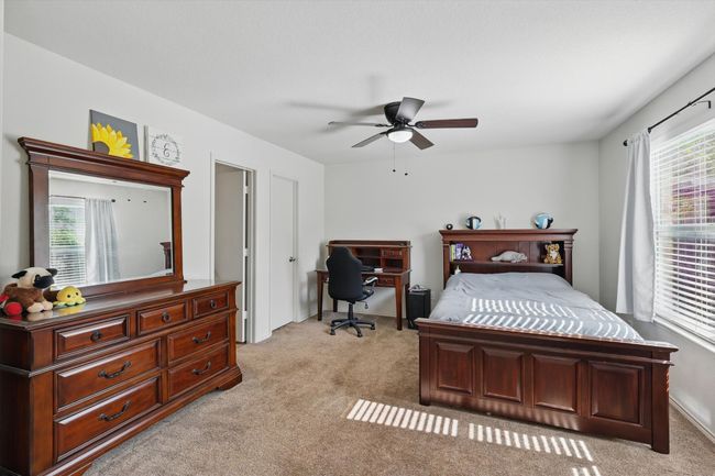 Bedroom featuring light carpet, multiple windows, an office area, and ceiling fan | Image 15