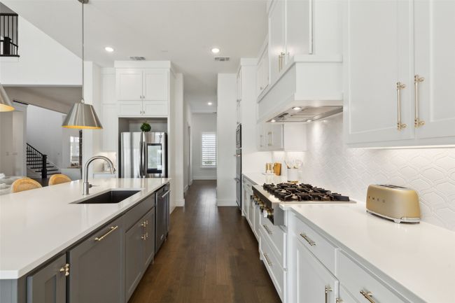 Kitchen featuring a sink, stainless steel appliances, white cabinetry, light countertops, and backsplash | Image 12