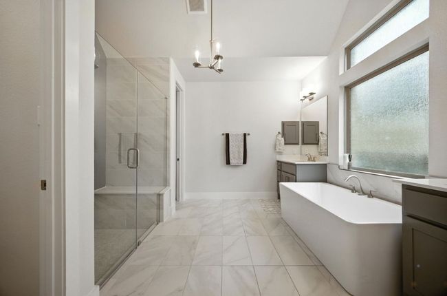 Full bathroom featuring marble look tile flooring, vanity, a shower stall, and a freestanding tub | Image 22