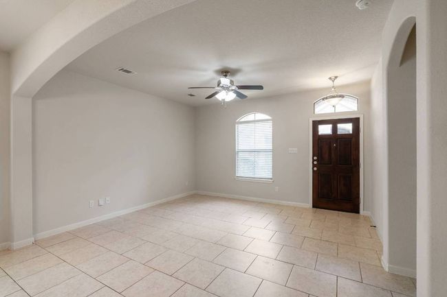 View of spacious living room and entry with beautiful wooded door. Archway to the left leads to the primary bedroom suite. | Image 8