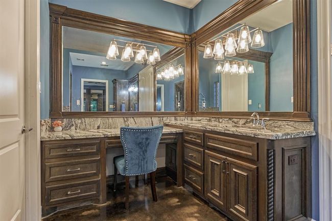 A closer look at the seated vanity area reveals the rich wood cabinetry and the intricate beauty of the granite countertops, highlighting the craftsmanship and attention to detail throughout the space. | Image 31