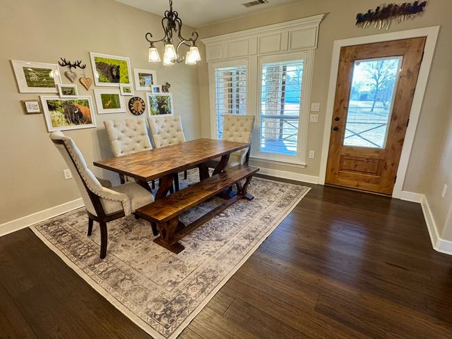 Dining space featuring dark wood-type flooring, baseboards, visible vents, and a chandelier | Image 10