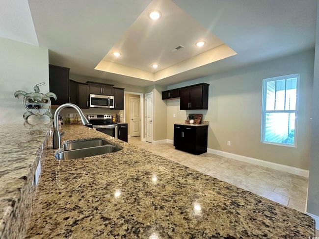 Kitchen featuring appliances with stainless steel finishes, light stone counters, recessed lighting, a raised ceiling, and a sink | Image 4