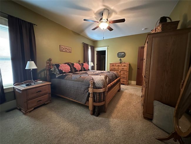 Bedroom featuring multiple windows, light carpet, a ceiling fan, and a spacious closet | Image 12