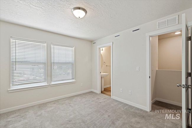 Unfurnished bedroom featuring light carpet, a textured ceiling, and ensuite bath | Image 12