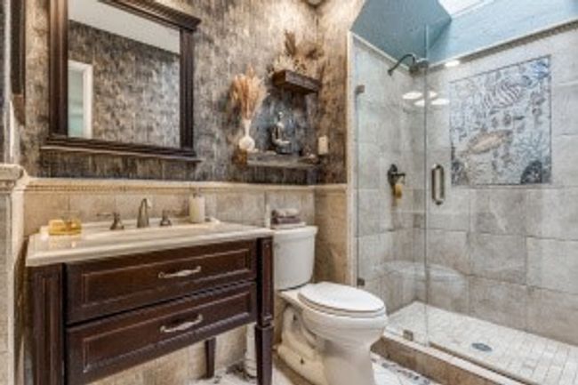 Bathroom featuring a shower stall, toilet, vanity, and a wainscoted wall | Image 21