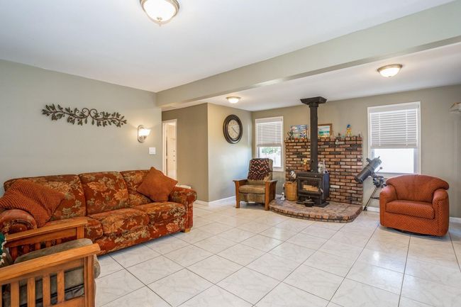 Living area featuring baseboards, a wood stove, and light tile patterned floors | Image 9