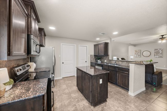 Kitchen with appliances with stainless steel finishes, dark brown cabinetry, a kitchen island, a peninsula, and recessed lighting | Image 11