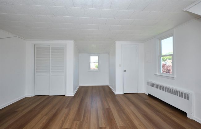 Bedroom with radiator heating unit, dark wood-style floors, and baseboards | Image 21