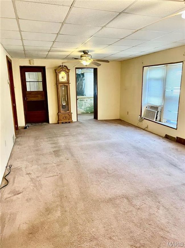 Unfurnished living room with light colored carpet, a drop ceiling, cooling unit, and ceiling fan | Image 4