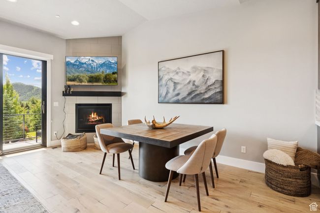 Dining room featuring vaulted ceiling, wood finished floors, a tiled fireplace, and recessed lighting | Image 9