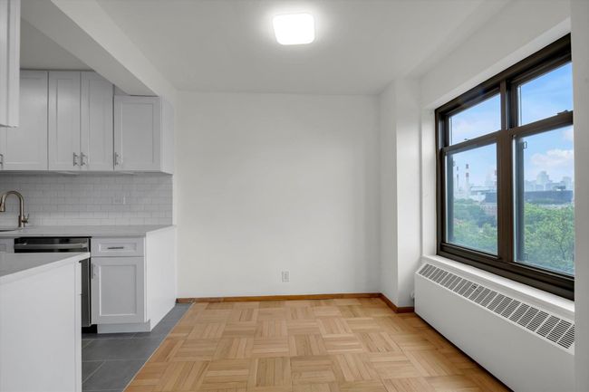 Kitchen featuring radiator heating unit, plenty of natural light, light countertops, and tasteful backsplash | Image 5