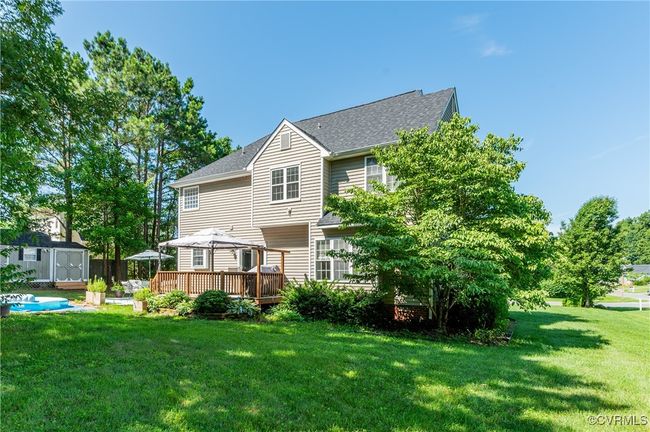 Rear view of house with a storage unit, a deck, a yard, and a shingled roof | Image 40