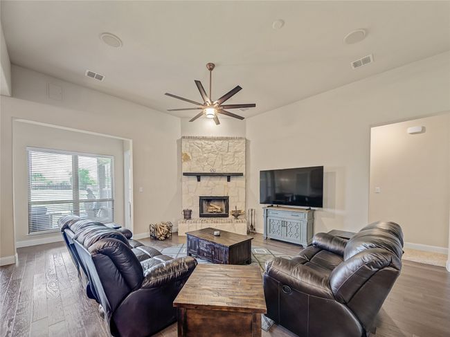 Living room with a ceiling fan, wood finished floors, and a fireplace | Image 17