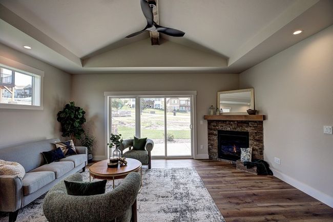 Living area featuring recessed lighting, lofted ceiling, a tray ceiling, a fireplace, and dark wood-style flooring | Image 17