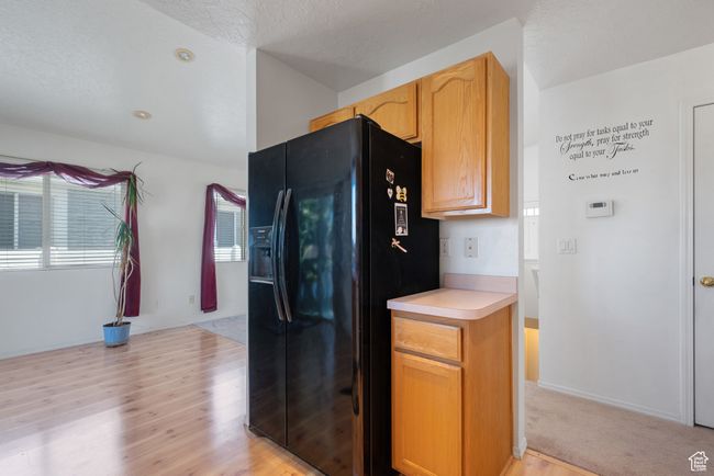 Kitchen with black fridge, light wood-style flooring, light countertops, and healthy amount of natural light | Image 10