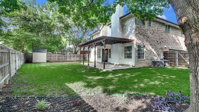 Rear view of house featuring a chimney, a patio area, a pergola, brick siding, and central AC unit | Image 23