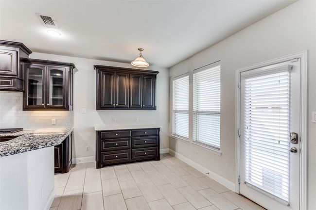 Kitchen featuring decorative backsplash, dark brown cabinetry, and light stone countertops | Image 10