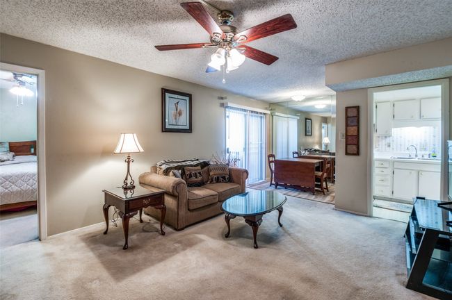 Living area with a ceiling fan, light colored carpet, and a textured ceiling | Image 6