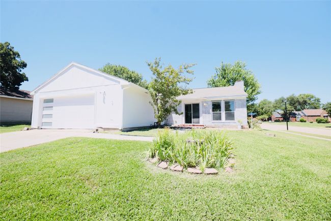 Ranch-style home with concrete driveway, a front lawn, a garage, and brick siding | Image 35