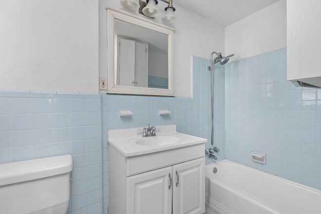 Bathroom with toilet, tile walls, shower / tub combination, and vanity | Image 33