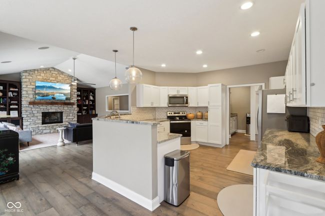 kitchen with open floor plan, white cabinets, light wood-style flooring, and appliances with stainless steel finishes | Image 17